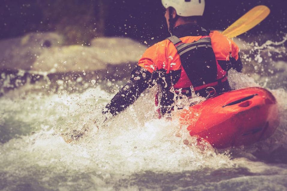 A guy is kayaking in rough water