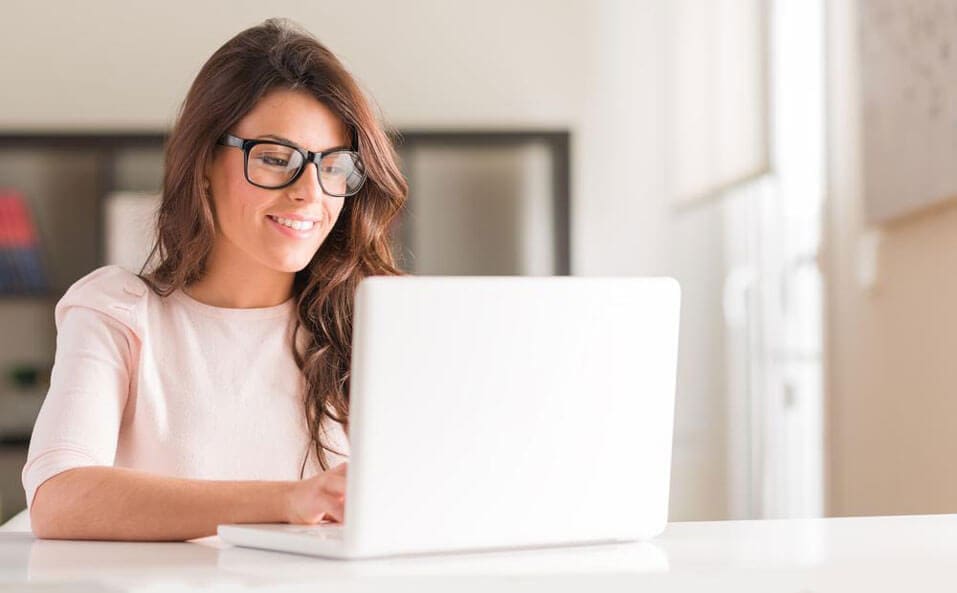 A brunette girl is searching the web on her laptop