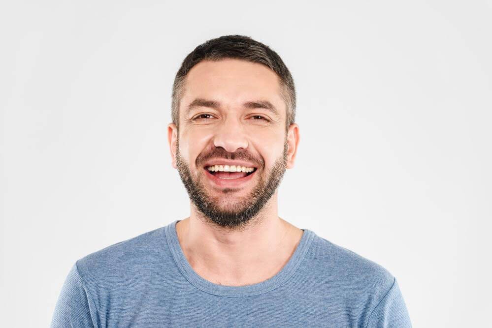 A middle-aged man with a beard is smiling.