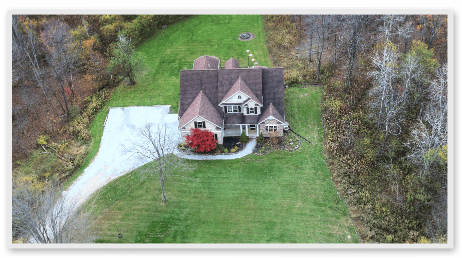 An aerial view of a house in the woods surrounded by nature.