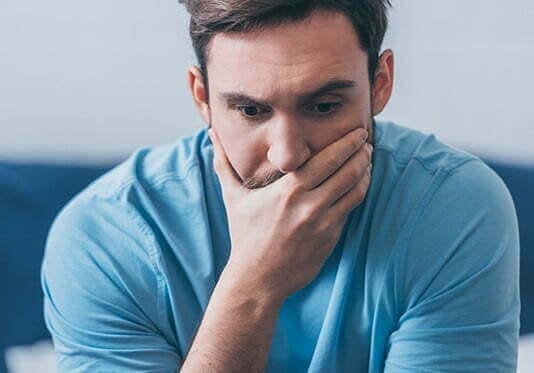 An addict with a hand over his face in drug rehab, seeking treatment for snorting meth
