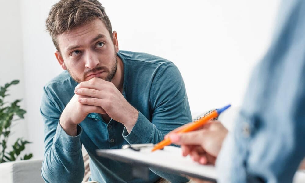 A man is sitting inside the office of someone explaining insurance to him.