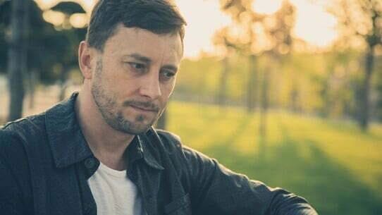 A man is sitting outside, experiencing detoxing from opioids.
