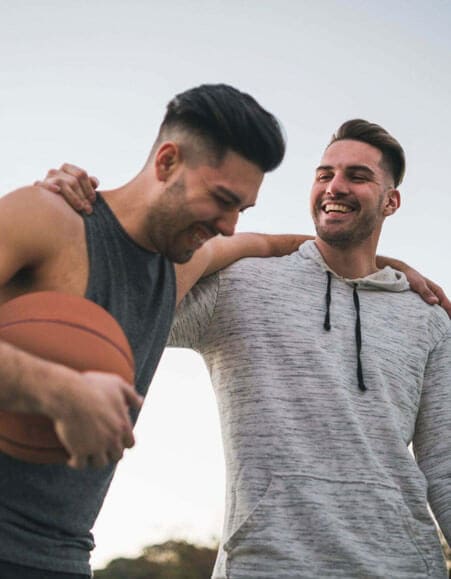 Two men are laughing on a basketball court.