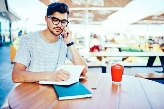 Man on phone writing in journal
