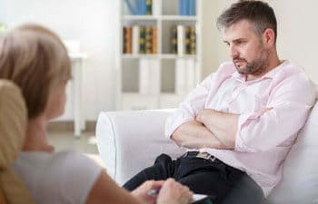 A therapist is listening to a man speak in her office.