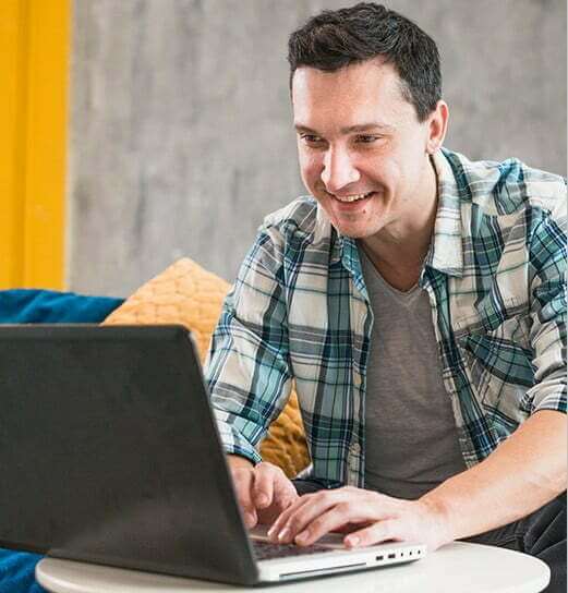 A guy in a flannel is using a computer.