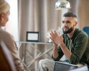 A man in a green shirt is listening to his counselor. 