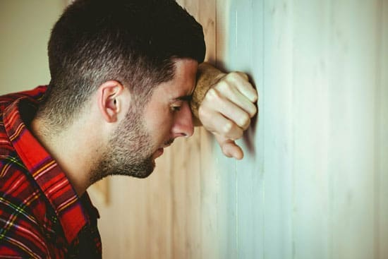 Man in a red flannel putting hand on a wall