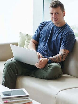 Man with tattoos sitting on computer 