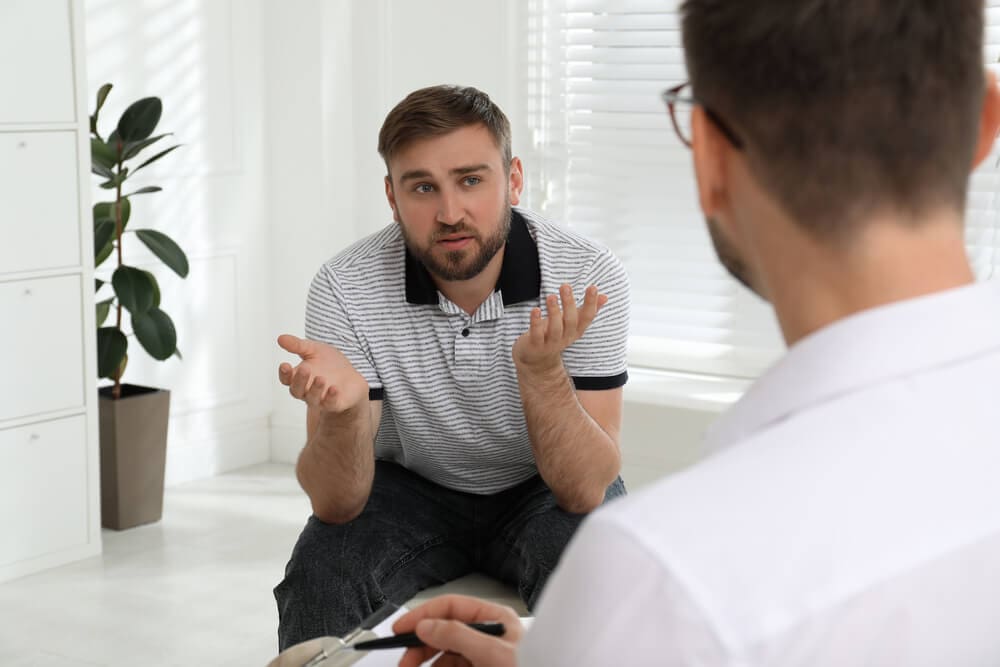 A man is talking to another man at a men's only rehab.