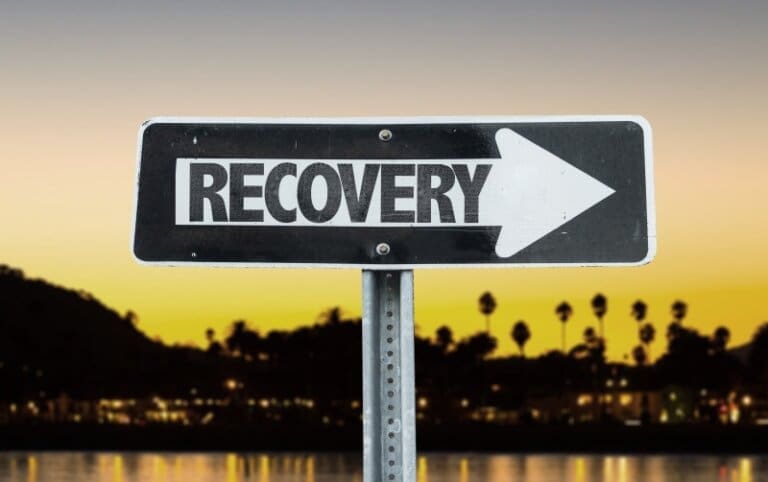 A black and white sign with the word rehab in front of a sunset, promoting an outpatient program.