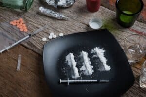 Syringes and pills on a black plate.