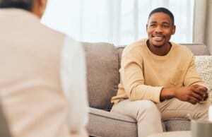 Two men discussing addiction recovery on a couch at an outpatient program.