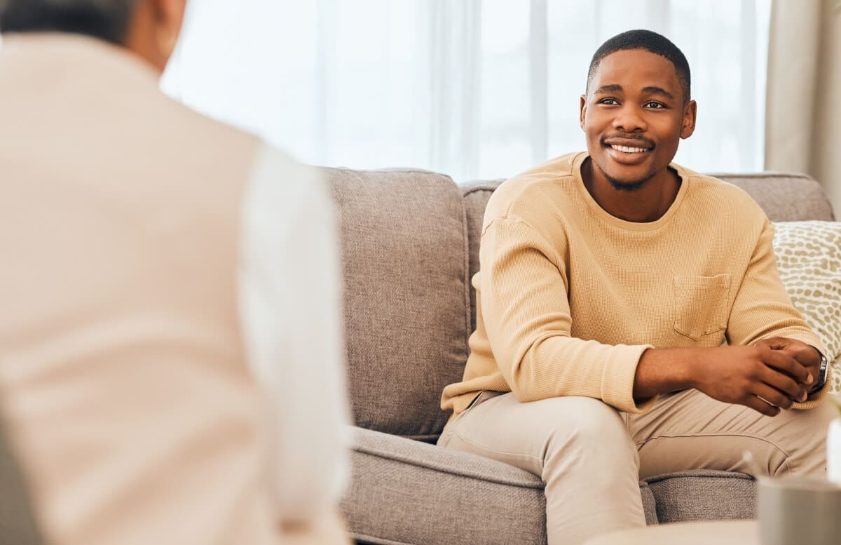Two men discussing addiction recovery on a couch at an outpatient program.