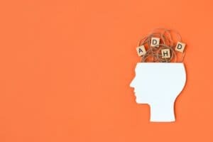 A man's head with wooden blocks in it, showcasing the word "ADHD" as he seeks understanding and support from an addiction recovery center.