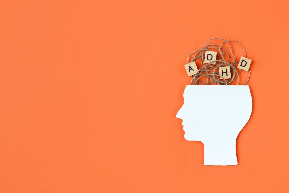 A man's head with wooden blocks in it, showcasing the word "ADHD" as he seeks understanding and support from an addiction recovery center.