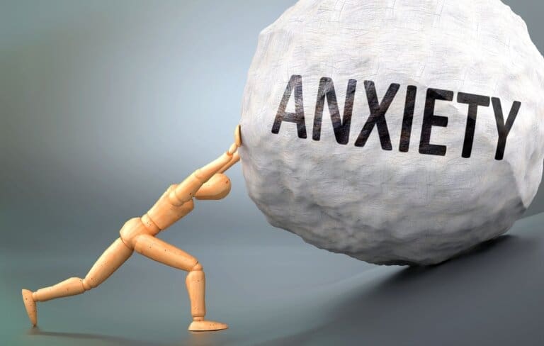 A man struggling with anxiety pushes a large rock, seeking relief through outpatient program or rehab treatment.