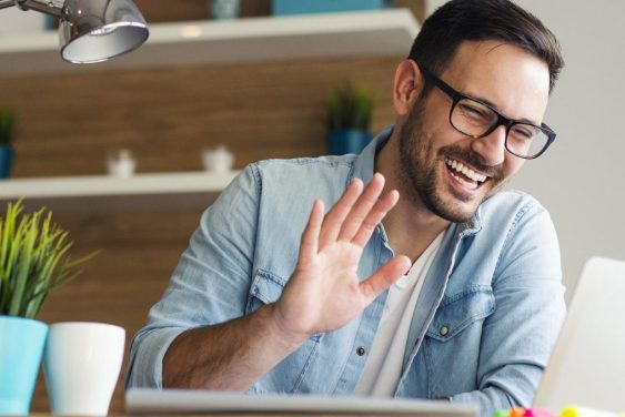 Remote job Smiling young man having video call and waving