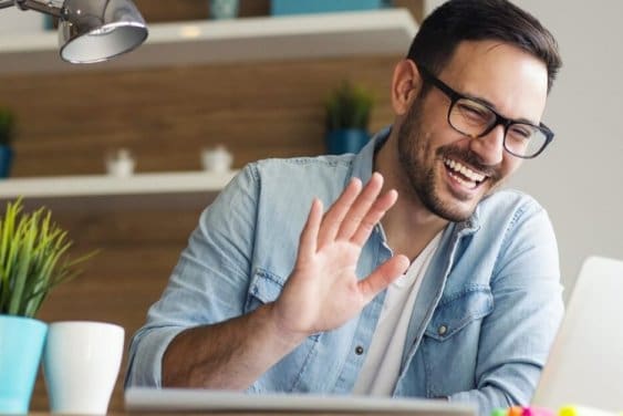 Remote job Smiling young man having video call and waving